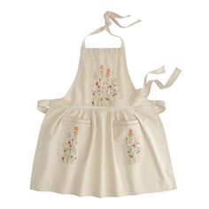 a white apron with flowers on it is hanging from the back of a child's dress