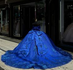 Make a royal entrance in this breathtaking royal blue quinceañera ball gown. The dress features a voluminous tulle skirt that flows gracefully into a chapel-length train, adding a majestic flair as you walk. The off-the-shoulder neckline adds a romantic and sophisticated touch, while the sleeveless design enhances the dress's elegant simplicity. The bodice is adorned with intricate appliques, creating a beautiful, textured effect that catches the light with every movement. A charming bow-knot at Royal Blue Quinceanera Dresses With Bow, Quinceanera Dresses With Train, Royal Blue Quince Dress, Quince Royal Blue, Royal Blue Ball Gown, Royal Entrance, Robes Quinceanera, Royal Blue Quinceanera Dresses, Dresses With Train