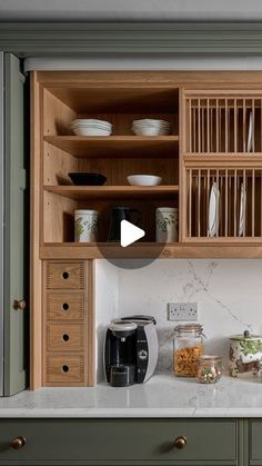 a kitchen with green cabinets and white counter tops, an open shelf above the sink