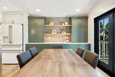 a large wooden table sitting in the middle of a kitchen next to an open door