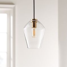 a glass light fixture hanging from a ceiling in a room with white walls and windows