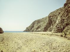 a rocky beach next to the ocean under a blue sky