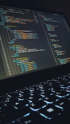 a laptop computer sitting on top of a black table covered in programming code numbers and symbols