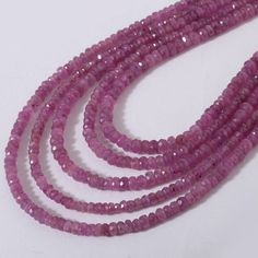 three strands of pink glass beads on a white surface