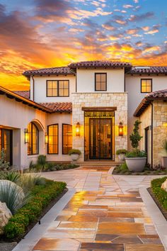 the front entrance to a large home with stone walkway leading up to it at sunset