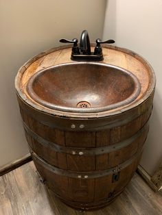 a wooden barrel sink sitting on top of a wood floor next to a white wall