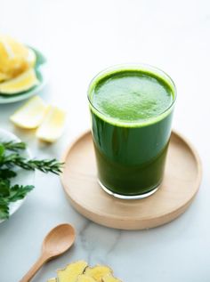 a cup of green liquid sitting on top of a wooden plate