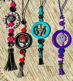 four different necklaces are hanging on a piece of cloth with beads and tassels