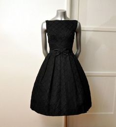 a mannequin wearing a black dress with a bow at the waist