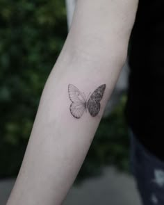 a small butterfly tattoo on the left inner arm and wrist, it is black and white