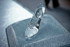 a glass object sitting on top of a metal table next to a person walking in the background