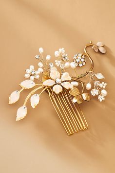 a hair comb with flowers and pearls on it sitting on a tan surface next to a pair of scissors