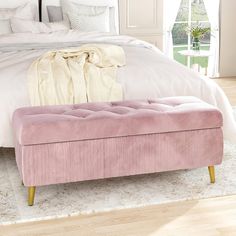 a pink bench sitting on top of a bed next to a white comforter and pillows