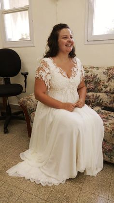 a woman in a wedding dress sitting on the floor next to a couch and chair