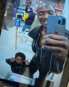 a man taking a selfie with his cell phone in front of the store window