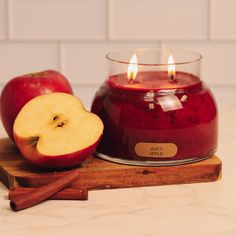 an apple sits next to a candle on a cutting board