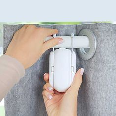 a woman is holding onto the curtain with her hand while using an electric toothbrush