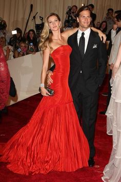 a man in a tuxedo and woman in a red dress at an event