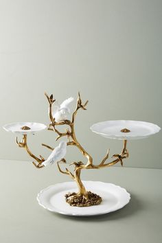 a white plate topped with two birds sitting on top of a tree shaped cake stand