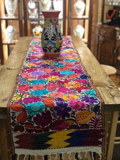 a vase sitting on top of a wooden table covered in colorful fabric and beading