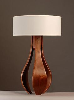 a wooden table lamp with a white lampshade on the top and bottom part