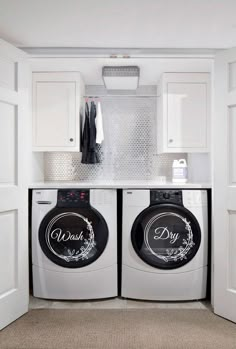 a washer and dryer in a laundry room with white cabinets on the wall