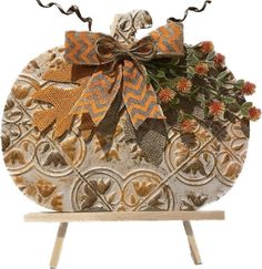 an orange and brown bow on top of a white pumpkin shaped box with flowers in it