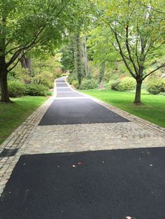 a paved road with trees and grass on both sides