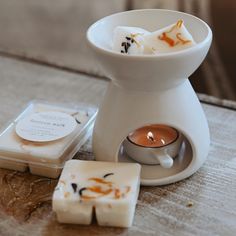 a candle and some soaps sitting on a table next to a small square coaster