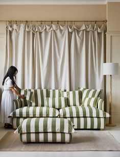 a woman standing next to a green and white striped couch