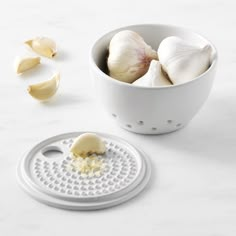 an onion grater next to garlic on a white counter