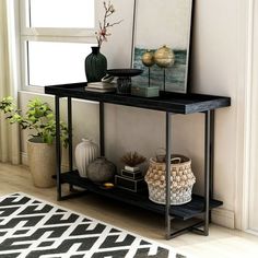 a black shelf with vases and pictures on it in front of a large window