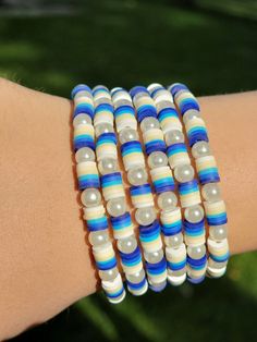 a close up of a person's arm wearing bracelets with blue and white beads