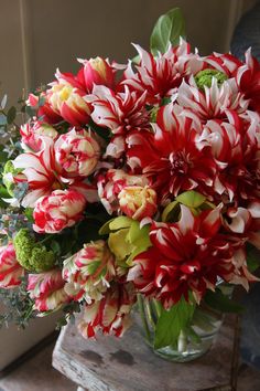 a vase filled with lots of red and white flowers on top of a wooden table