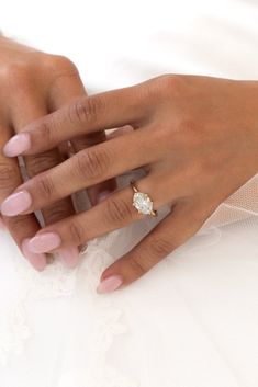 a close up of a person's hand with a ring on their finger and wedding dress in the background