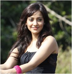 a beautiful young woman in a black dress holding onto a pink wristband with trees in the background