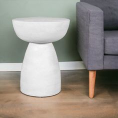 a white table sitting on top of a wooden floor next to a gray couch and chair