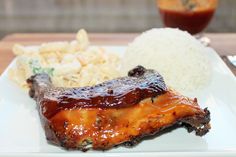 a white plate topped with ribs, rice and cole slaw