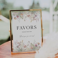 a sign that says favors on it sitting on top of a wooden table next to feathers