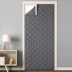 an open door with a grey quilted cover on it and a lamp next to it