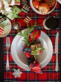 a christmas table setting with red and green plaid napkins, silverware, crackers, peppermint sprigs