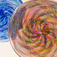 two glass bowls with different colored swirls in the bottom one is blue and the other has yellow