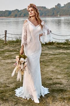 a woman in a white dress is standing by the water