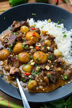 a blue plate topped with meat and potatoes covered in gravy next to rice