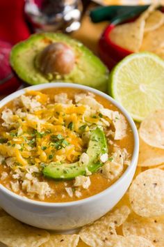 a white bowl filled with salsa and tortilla chips next to an avocado