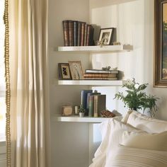 a bedroom with white walls and shelves filled with books, plants, and other items