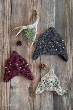 three crocheted hats sitting on top of a wooden floor next to an air plant