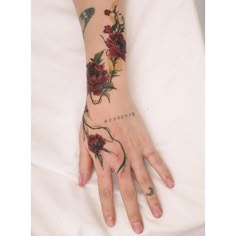 a woman's hand with flowers on it and a bird flying over her arm