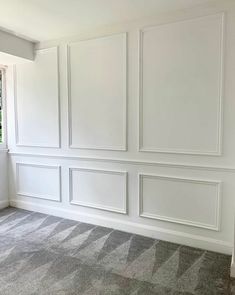 an empty room with white paneling and carpet