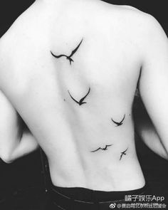 a black and white photo of a woman's back with birds flying around her